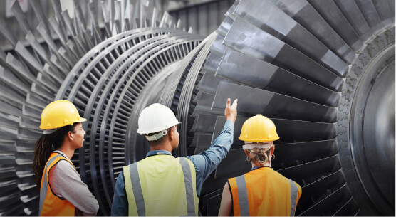 Three people examining large industrial turbine