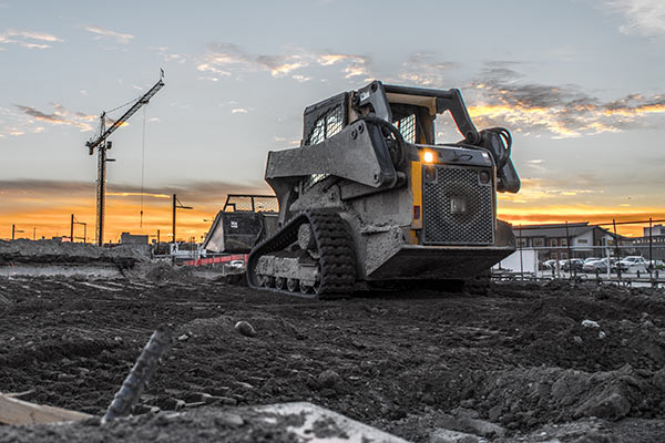 Photo of rear of construction equipment at site with crane in background.