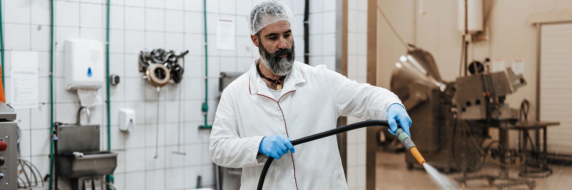 Photo of man washing down machinery.
