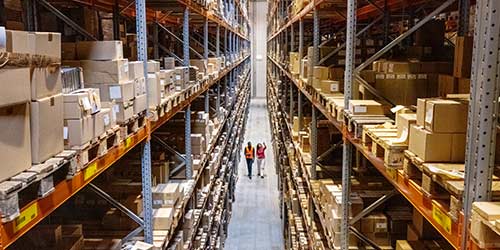 Overhead shot of warehouse with filled shelves and two people walking.