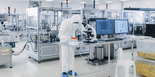 Technician writing notes in pharmaceutical lab.