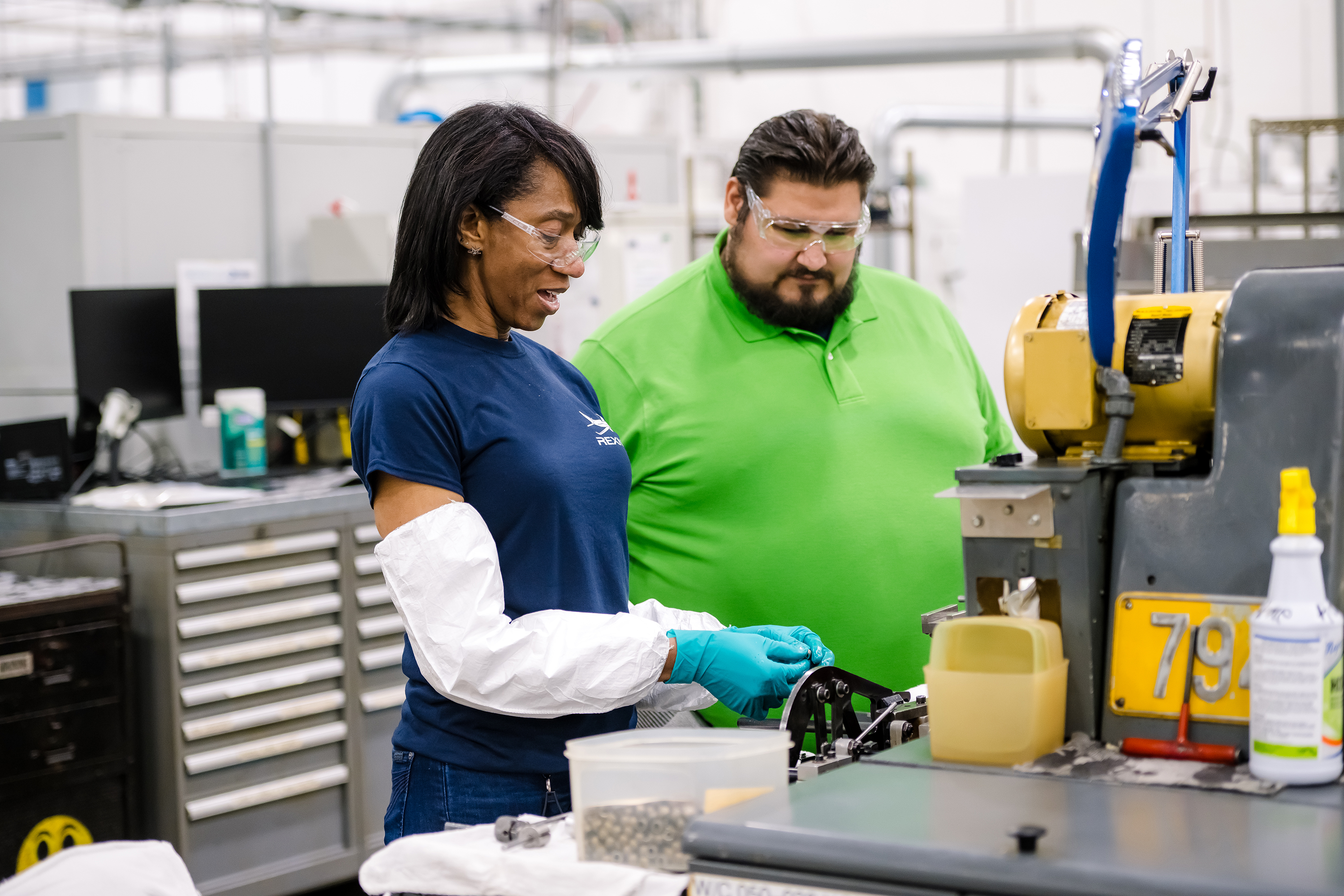 Two Regal Rexnord associates standing together at a work station, looking at an item being held by one of the associates