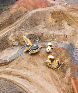 Three earth moving machines including a backhoe loader at a quarry