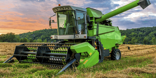 Green combine in a field in the morning