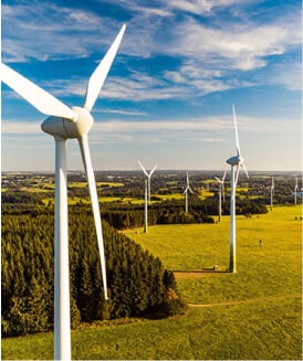Windmills in windfarm rise above fields and trees