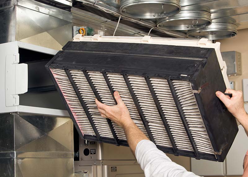 Photo of person's hands installing a large commercial HVAC system filter.