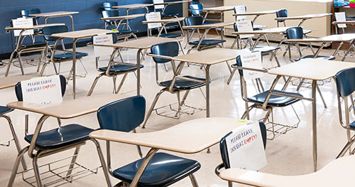 Photo of desks in a classroom, with some desks blocked off for social distancing.