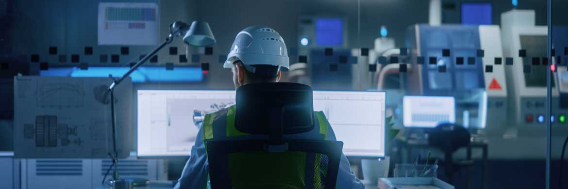 Photo of technician in hard hat monitoring computer screens.