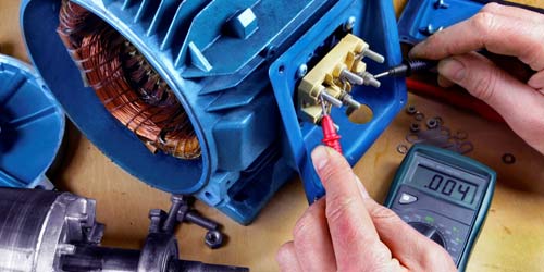Photo of open blue electric motor with hands attaching diagnostic tool.