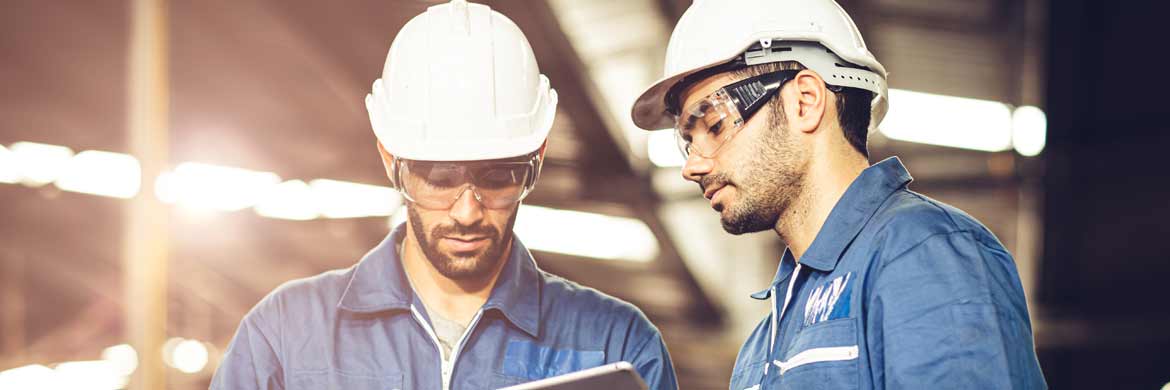 Photo of two engineers in hard hats looking at tablets.
