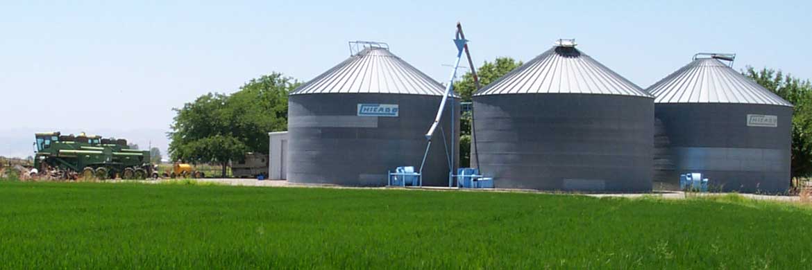 Photo of three silos on a farm with equipment nearby.