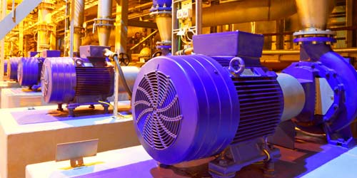 Row of blue pump motors in industrial plant.