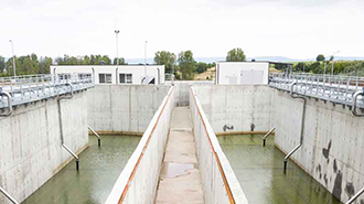 Image of a bridge with green water at the side and a lot of pipes